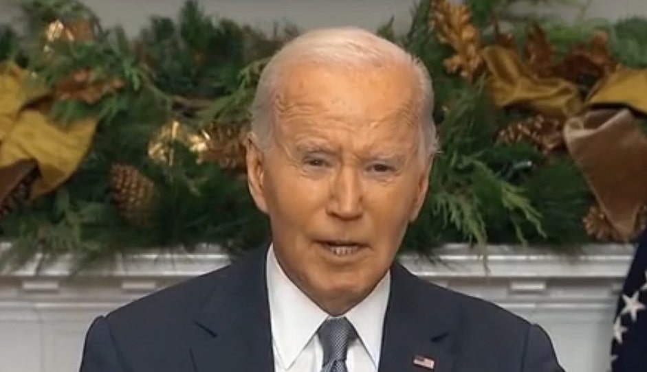 Picture of Biden at the White House in the Oval office in front of the fire plave with Christmas decorations