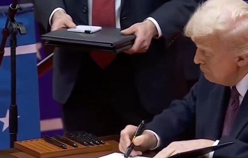 Picture of President Trump signing executive orders.